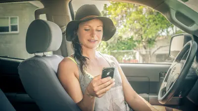 The image shows a women with smarphone in a car.