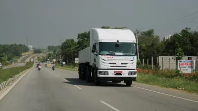 A large white commercial truck, prominently displaying "BOSCH" and "Hydrogen Engine" branding on its front grille, drives down a multi-lane highway. The truck is positioned slightly to the right of the center of the frame, moving towards the viewer.