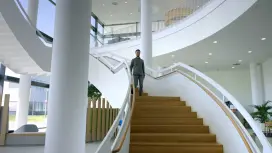 Patrick runs down a staircase and smiles.