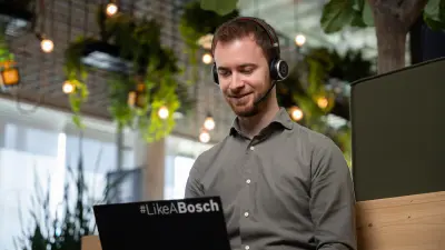 Patrick sits in front of his laptop wearing headphones and is on a call with someone.