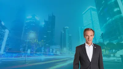 Dr. Volkmar Denner in the forground and a busy street at night in the background.
