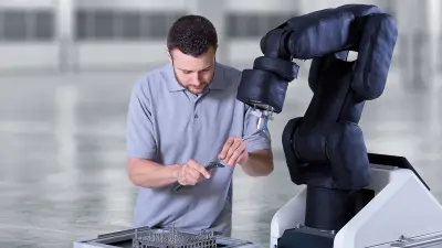 A man sitting on the floor and repairing a robot.