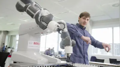 Ein Mann steht direkt neben einem Roboterarm