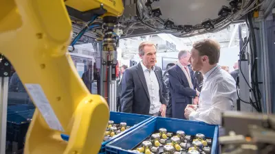 Dr. Volkmar Denner hinter dem Roboterarm ViPAS bei der Sichtprüfung von Produktionsteilen