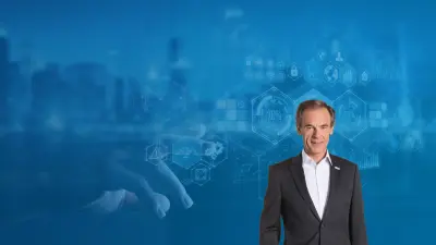 Dr. Volkmar Denner in the foreground. A hand pointing at a futuristic data screen in the background.