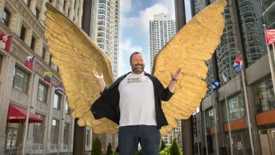 Alfons Müller steht mitten in Chicago vor zwei goldenen Engelsflügeln. Es sieht so aus, als würden diese direkt aus seinem Rücken kommen.