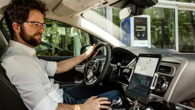 Christian Heise in einem Auto, er schaut auf das Tablet, auf dem sein Software-Agent installiert ist.