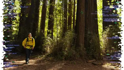 Der Feuerwehrmann Ricky Staley läuft in Uniform mit seinem Helm unter dem Arm durch einen Wald. An einem Baum hängt ein grüner Sensor zur Brandgaserkennung.