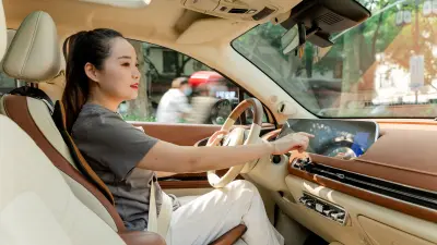 Cao Mengyi behind the wheel of her Ora Good Cat. She taps the display in front of her.