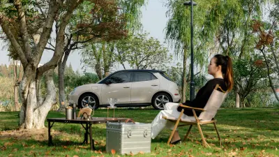 Cao Mengyi sitting on a chair in the park in front of her car Ora Good Cat.