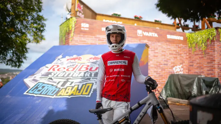 Mountain biker in helmet stands with a bike in front of a Red Bull ramp in Stuttgart.