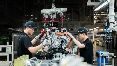 Associates lift an e-axle into the frame of an electric vehicle.