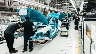 Tow associates and a Xiaomi SU7 in a production line at a plant.