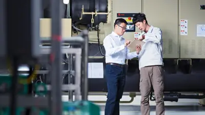 Bosch-Mitarbeiter Honghui Wu schaut mit einem Kollegen zusammen auf ein Tablet. Im Hintergrund ist eine Maschine zu sehen, die Teil des Kühlwassersystems im Bosch-Werk Qingdao ist.