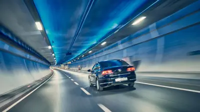 A car drives through the Eurasia Tunnel. The tunnel has a illuminated ceiling with blue light.