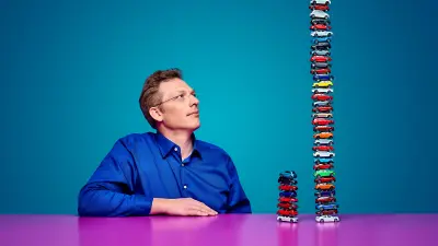 Sebastian Krieger looking at two stacks of toy cars of different heights