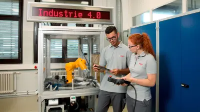 Two apprentices in front of an industrial robot.