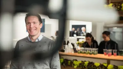 Tobias Menne stands in front of a shop which sells organic grocerys.