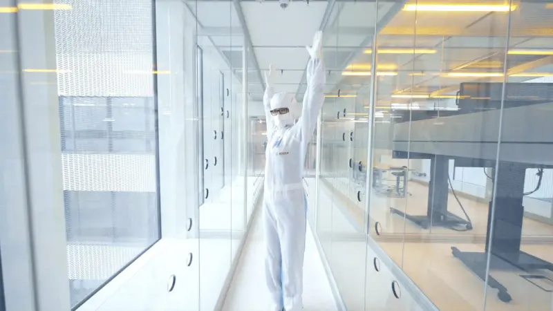 Standing in an airlock with her protective suit on, Sarah Fischbach looks back over her shoulder.