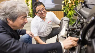 Zwei Personen hocken neben einer Kawasaki.