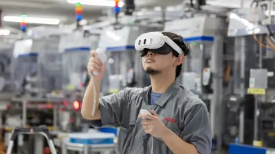 Person mit VR-Headset und Controllern in Fabrikumgebung mit Maschinen.