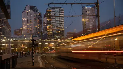 Vor der nächtlichen Skyline von Den Haag fährt eine Straßenbahn um eine Kurve. Sie ist durch die Bewegungsunschärfe nur als Kontur erkennbar.