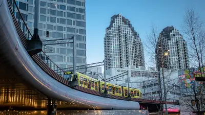 Eine Straßenbahn fährt auf einer Trasse durch Den Haag. Im Hintergrund sind moderne Hochhäuser zu sehen.