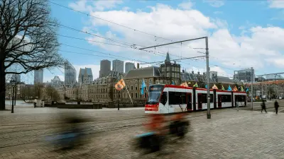 : Eine Straßenbahn fährt über einen großen Platz in Den Haag, im Hintergrund sind Häuser zu sehen.