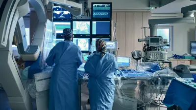 Zwei Krankenhausmitarbeiter in blauer Arbeitskleidung in einem Herzkatheterlabor