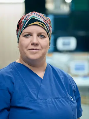 Porträt von Jessica Rama mit blauer Krankenhausbekleidung und buntem Kopftuch