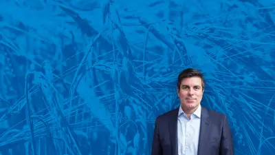Jean-Marie Sol, Group Agronomy Director von Bonduelle, vor einem transparenten blauen Hintergrund, der ein Weizenfeld zeigt.