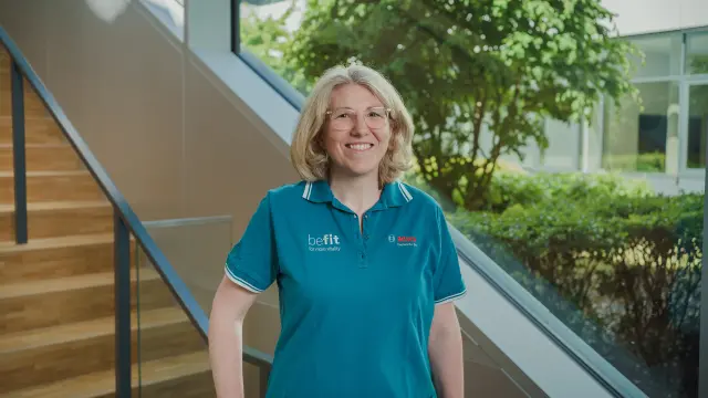 Antje stands in front of a staircase and smiles at the camera.