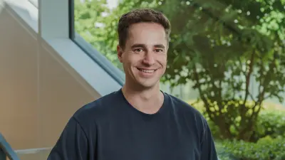 Max stands in front of a staircase and smiles at the camera.