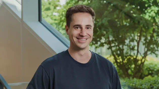 Max stands in front of a staircase and smiles at the camera.