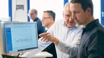 Zwei Bosch-Mitarbeiter stehen an einem Schreibtisch, blicken auf einen Bildschirm und analysieren Daten einer Heizungsanlage.
