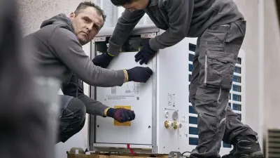 Zwei Männer bereiten eine Wärmepumpe von Bosch für die Installation vor.