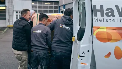 Vier Männer laden eine verpackte Wärmepumpe von Bosch in einen Transporter.