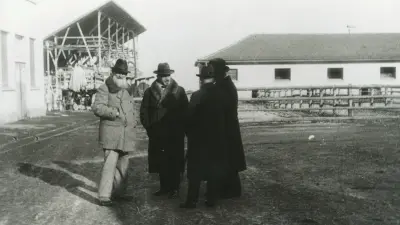 Four men in the yard of a large farm