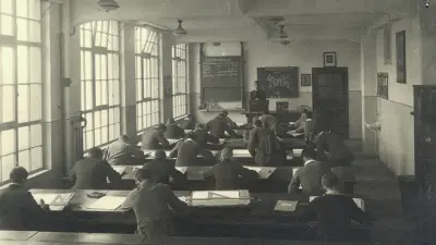 Classroom with occupied benches and teacher at the blackboard