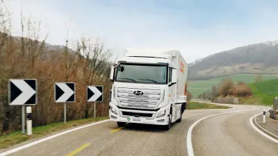 The hydrogen truck approaches the observer at speed, taking a curve. In the background, an idyllic Swiss landscape.