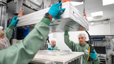 Workers handling a large component with precision tools.