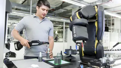 A man is working together with the robot at the same desk.