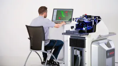 A man sitting in front of a computer next to the APAS inspector.