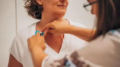 Sensor being attached to the upper chest of a person wearing a white shirt