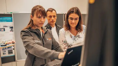 Three people working together at a computer in a test environment