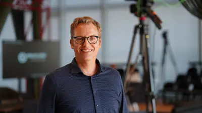 Person with glasses standing in front of a camera setup