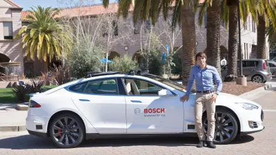 Ein Mann steht vor einem Tesla-Auto.