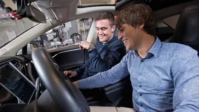 Zwei Männer sitzen im Cockpit eines selbstfahrenden Tesla-Autos.