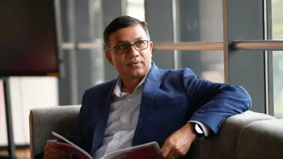Guruprasad Mudlapur, a man with short dark hair and black-rimmed glasses, with a light blue shirt and a medium blue suit.