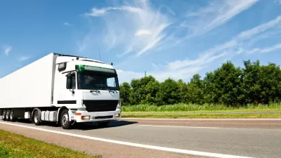white truck on a road with trees and blue sky